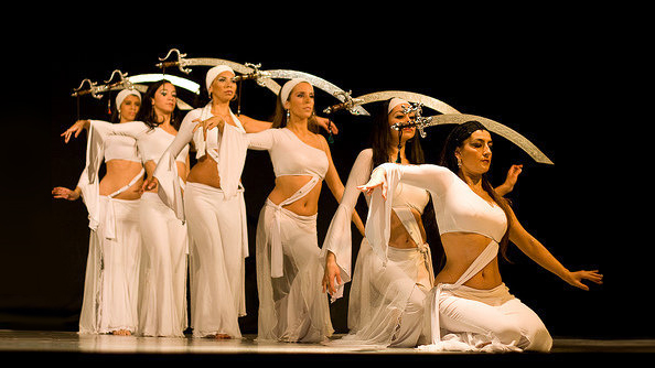 Presentación de gala de danza árabe con bailarinas en escenario, luciendo vestuarios Manal diseñados a medida.
