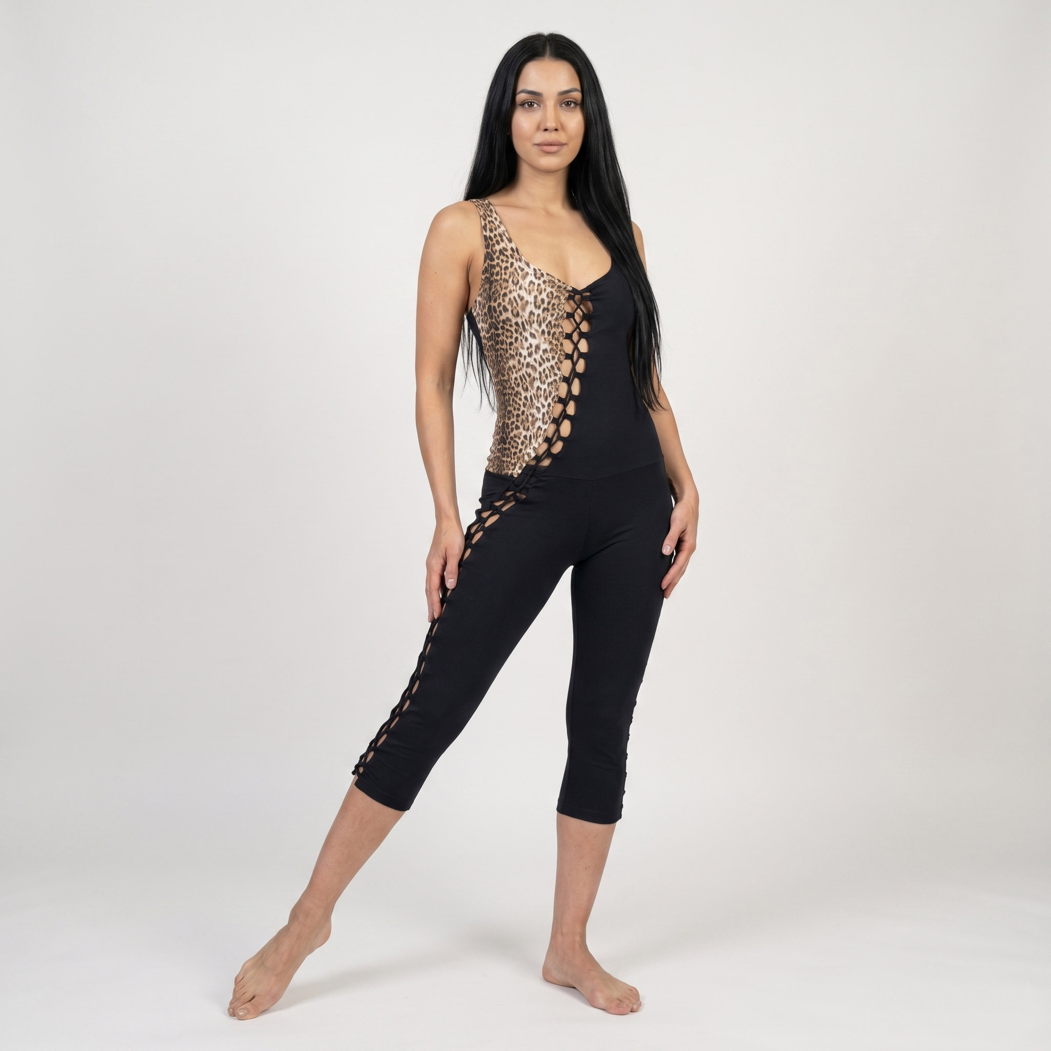 Modelo posando un entetito tipo cat suit de algodón brasilero en un diseño exclusivo que combina dos telas: algodón negro y algodón animal print. Lleva un entrelazado en toda la unión de ambas telas con cordeles tipo lace out.