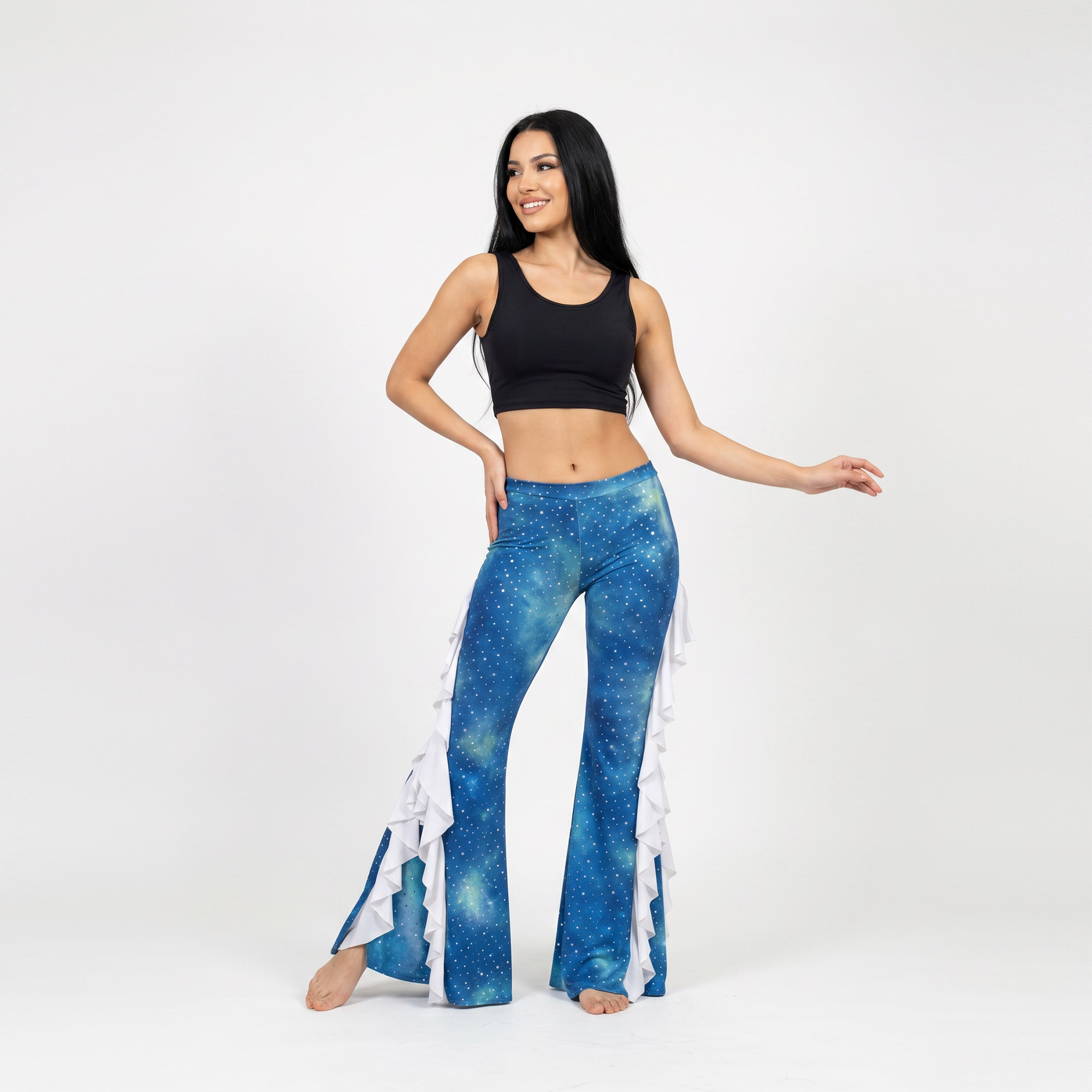 Modelo posando un pantalón de lycra batik en tonos celeste, azul batik. Diseño acampanado con vuelos en color blanco. El pantalon pose aberturas laterales donde van los vuelos. Diseño unico para Danza Practica y Performance