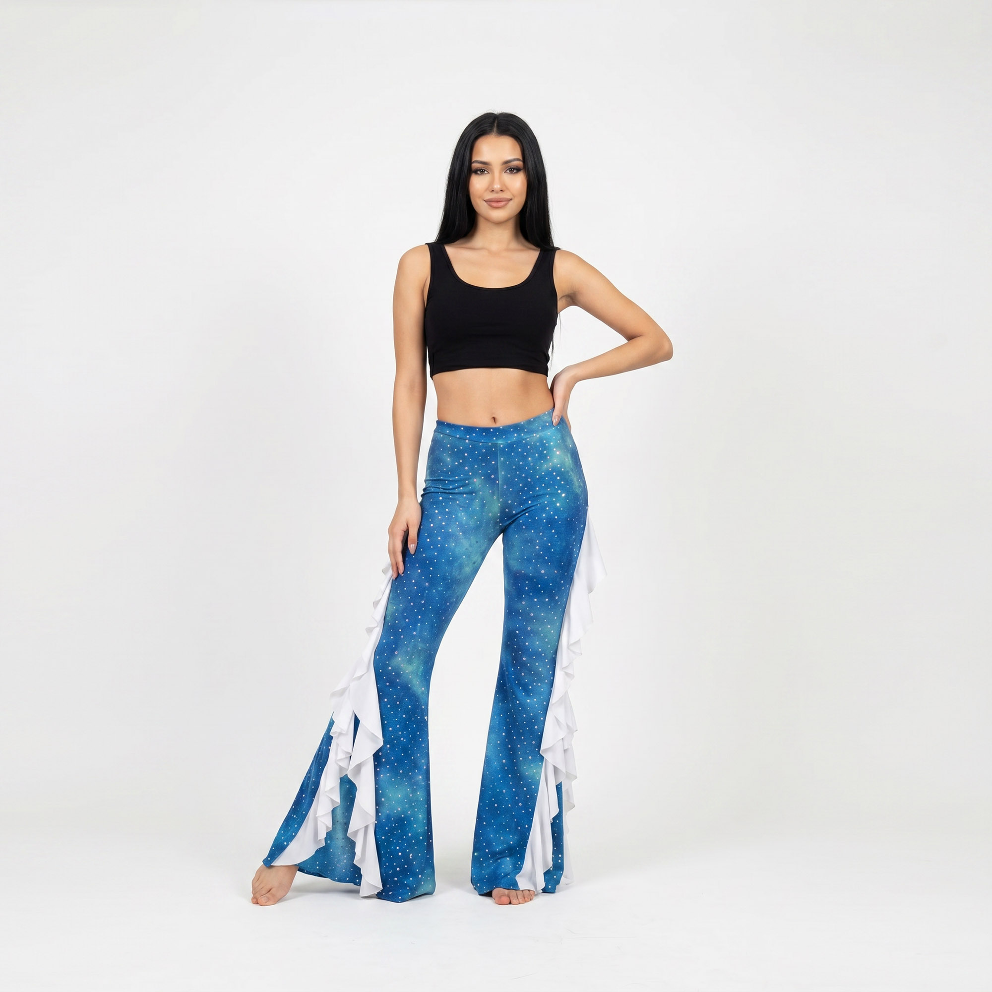 Modelo posando un pantalón de lycra batik en tonos celeste, azul batik. Diseño acampanado con vuelos en color blanco. El pantalon pose aberturas laterales donde van los vuelos. Diseño unico para Danza Practica y Performance