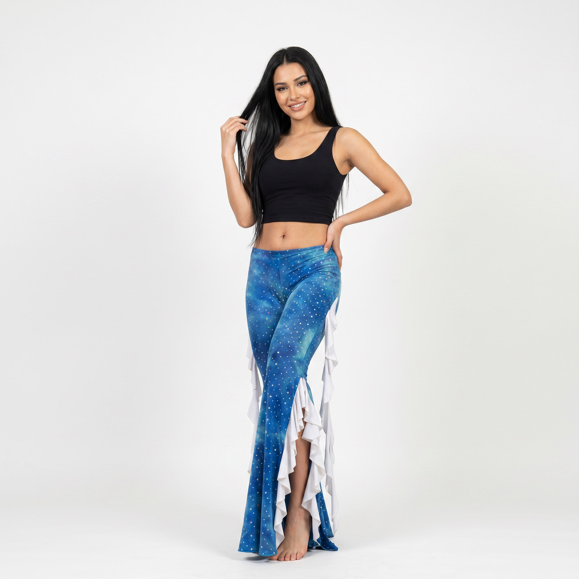 Modelo posando un pantalón de lycra batik en tonos celeste, azul batik. Diseño acampanado con vuelos en color blanco. El pantalon pose aberturas laterales donde van los vuelos. Diseño unico para Danza Practica y Performance