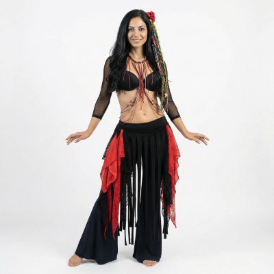 Mujer posando un vestuario de diseño exclusivo, estilo tribal rojo y negro. Le cuelgan muchos trozos de tela, flecos, collares, cadenas, colores negro y rojo, accesorios para el pelo con flores bordados, tejidos hechos a mano. Diseño exclusivo Manal.