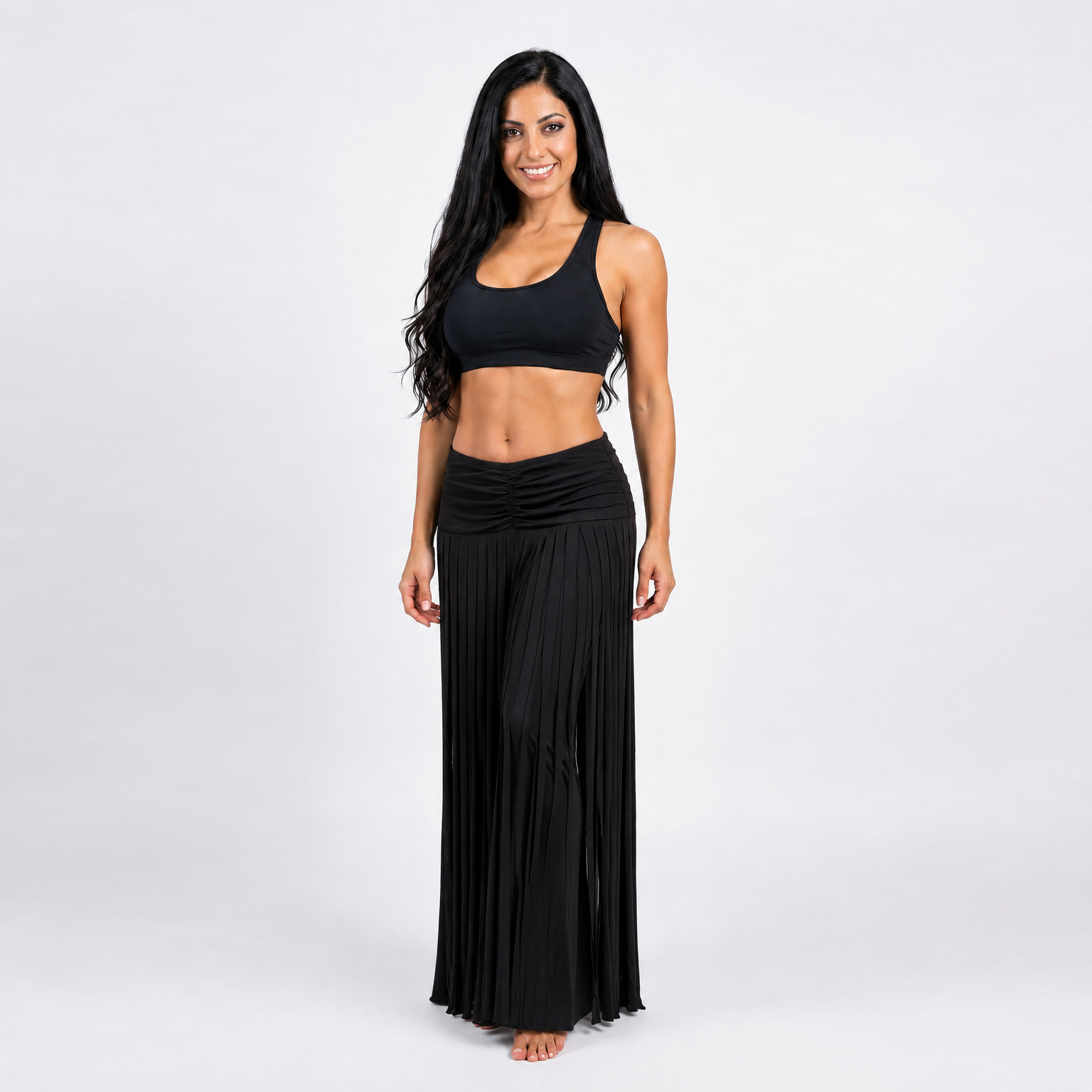 Modelo de danza usando un pantalón de Lycra con un faldón sobre este lleno de flecos en Lycra negra y un peto negro de Lycra.